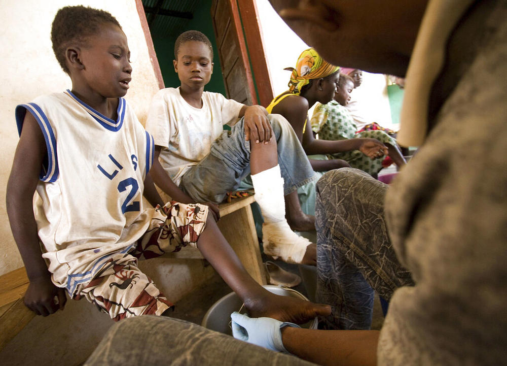 Lashidu Wahabu, 7, left, cries as a health worker extracts a Guinea worm from his ankle at a containment center in Savelugu, Ghana, Friday, March 9, 2007. The number of people infected with Guinea worm dropped to just over a dozen worldwide in 2021 as health workers try to eradicate the disease.