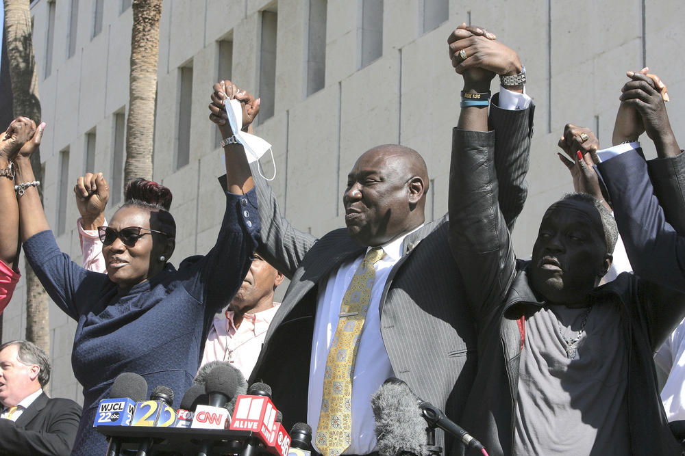 Attorney Benjamin Crump holds up the arms of Ahmaud Arbery's parents, Wanda Cooper-Jones and Marcus Arbery Tuesday, Feb. 22, 2022 outside the federal courthouse in Brunswick, Ga. The three men convicted of murder in Ahmaud Arbery’s fatal shooting have been found guilty of federal hate crimes. 
