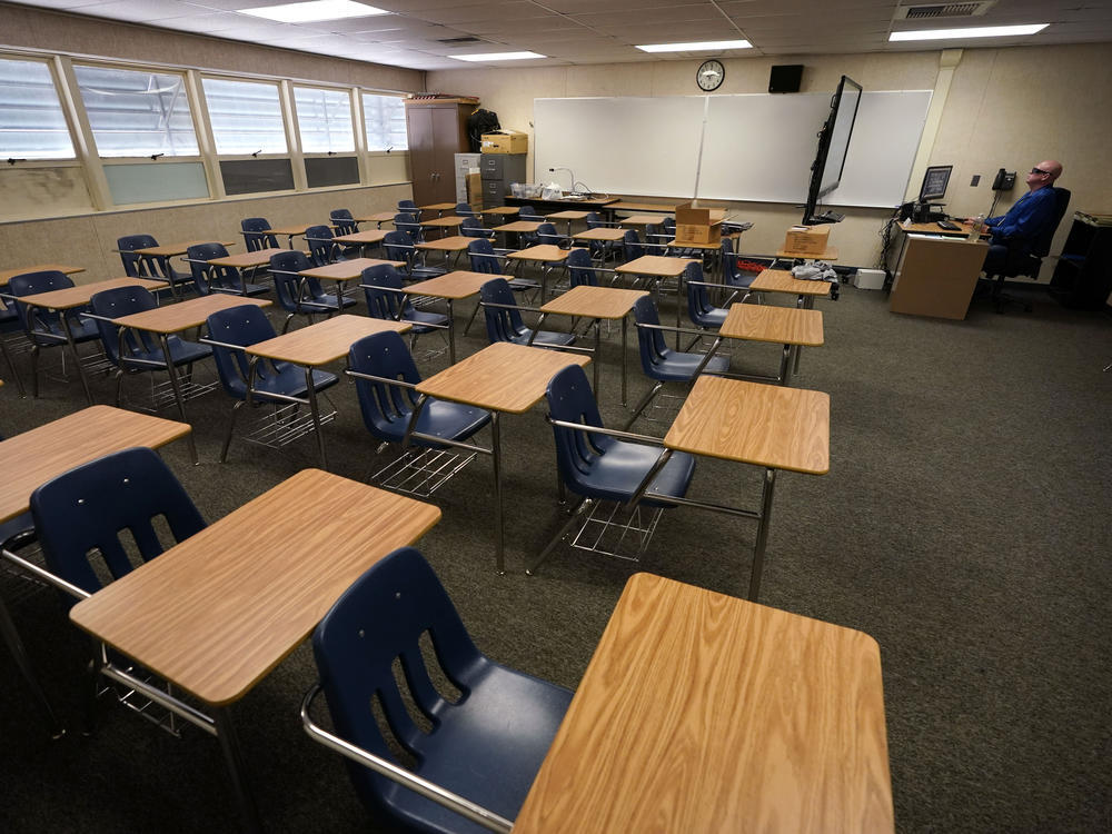 In this Aug. 18, 2020, file photo, math teacher Doug Walters sits among empty desks as he takes part in a video conference with other teachers to prepare for at-home learning at Twentynine Palms Junior High School in Twentynine Palms, Calif. California.