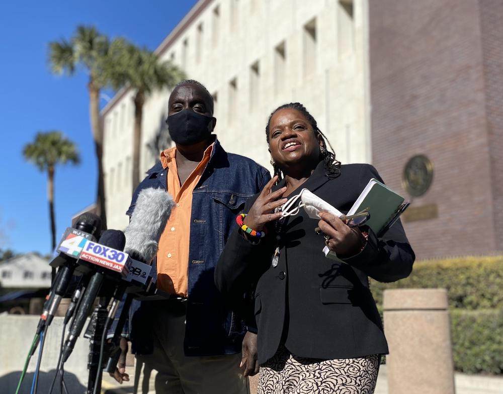 Ahmaud Arbery's father, Marcus Arbery, and civil rights lawyer Barbara Arnwhine address reporters outside the Brunswick federal courthouse on Feb. 14, 2022. Several news microphones are situated in front of them.