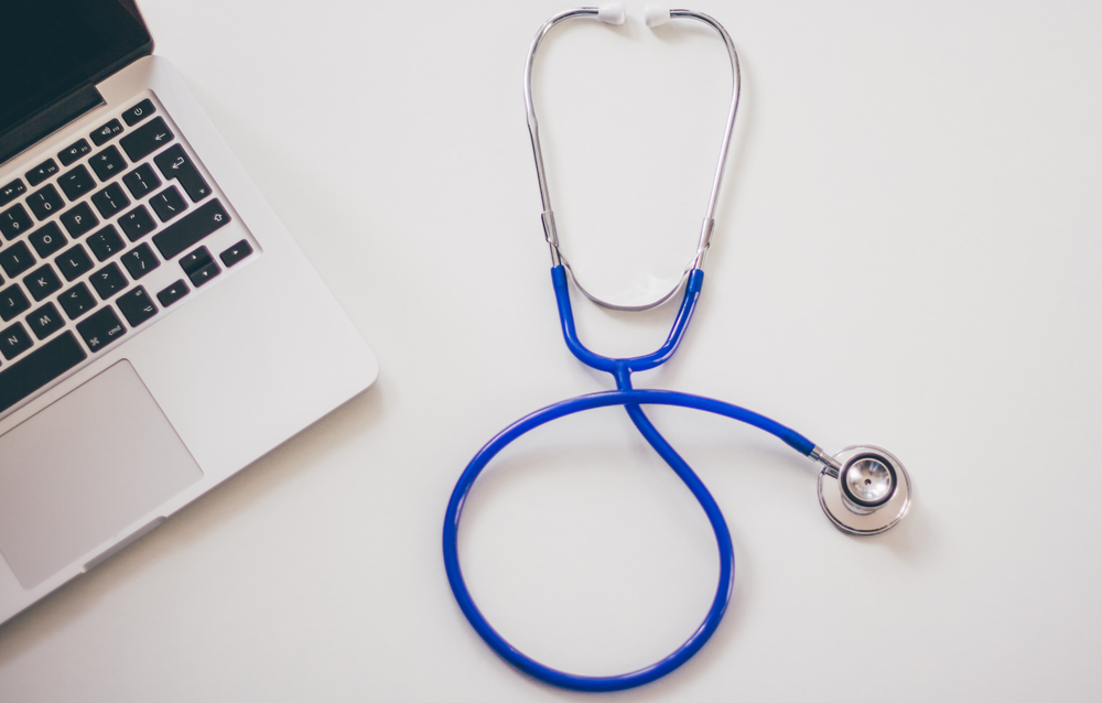 An image of a blue stethoscope and laptop computer