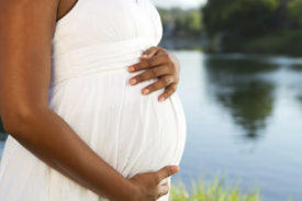 A pregnant woman cradles her womb.