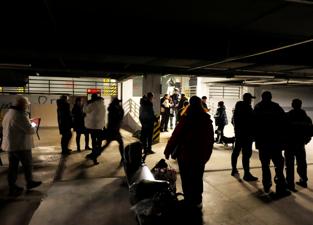 People stand in an underground parking used as a bomb shelter in a mall center in Odesa, Ukraine, Monday, Feb. 28, 2022. In makeshift shelters and underground railway platforms across Ukraine, families trying to protect the young and old and make conditions bearable amid the bullets, missiles and shells outside.