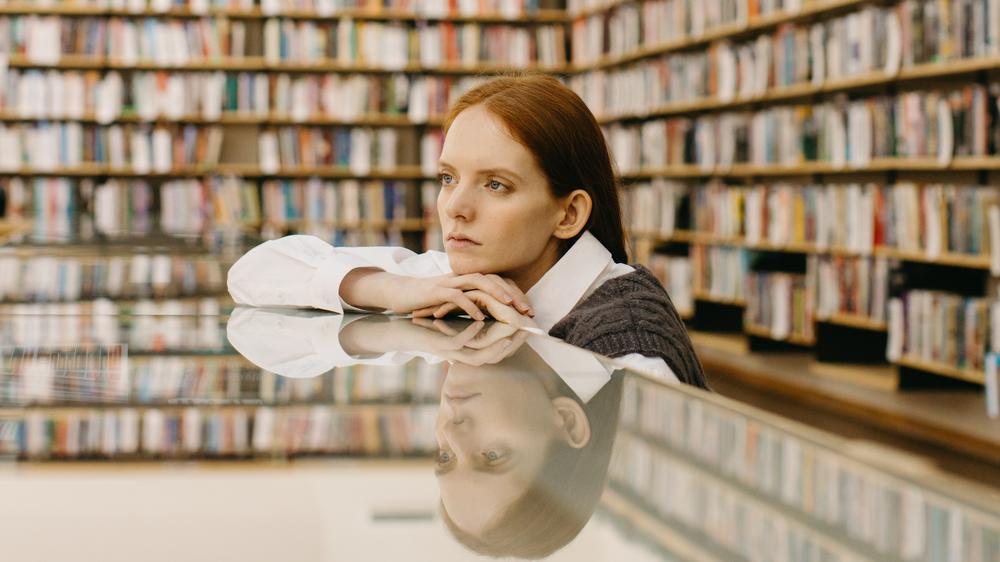 A woman sits at a table in a library
