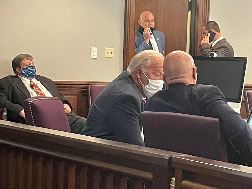 Camden County Commission Chairman Gary Blount chats with County Attorney John Myers as Probate Court Judge Robert C. Sweatt Jr sits off to the left in a hearing earlier this month.