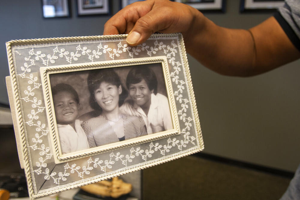 Robert Peterson holds a photo showing his late mother, Yong Ae Yue, on Thursday, March 10, 2022, in Atlanta. Yue was one of eight people shot and killed at various massage businesses on March 16, 2021, in the Atlanta area. Many family members and friends of the victims have been struggling with grief, trying to heal and making sure their loved ones aren't forgotten.