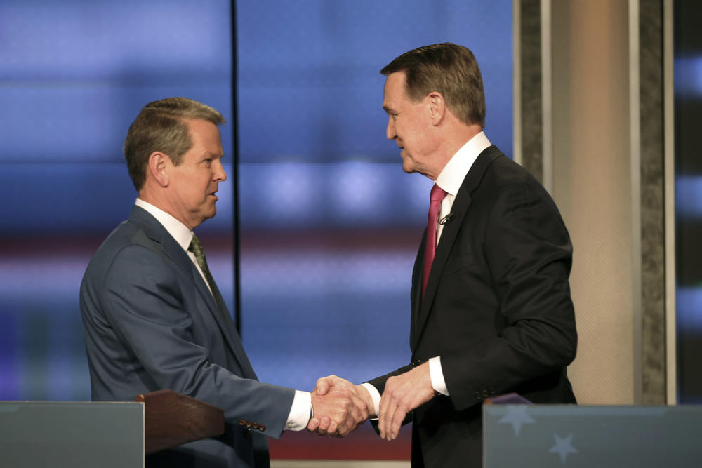 Georgia Gov. Brian Kemp, left, shakes hands with former Sen. David Perdue at a Republican gubernatorial debate, Sunday, April 24, 2022, in Atlanta.