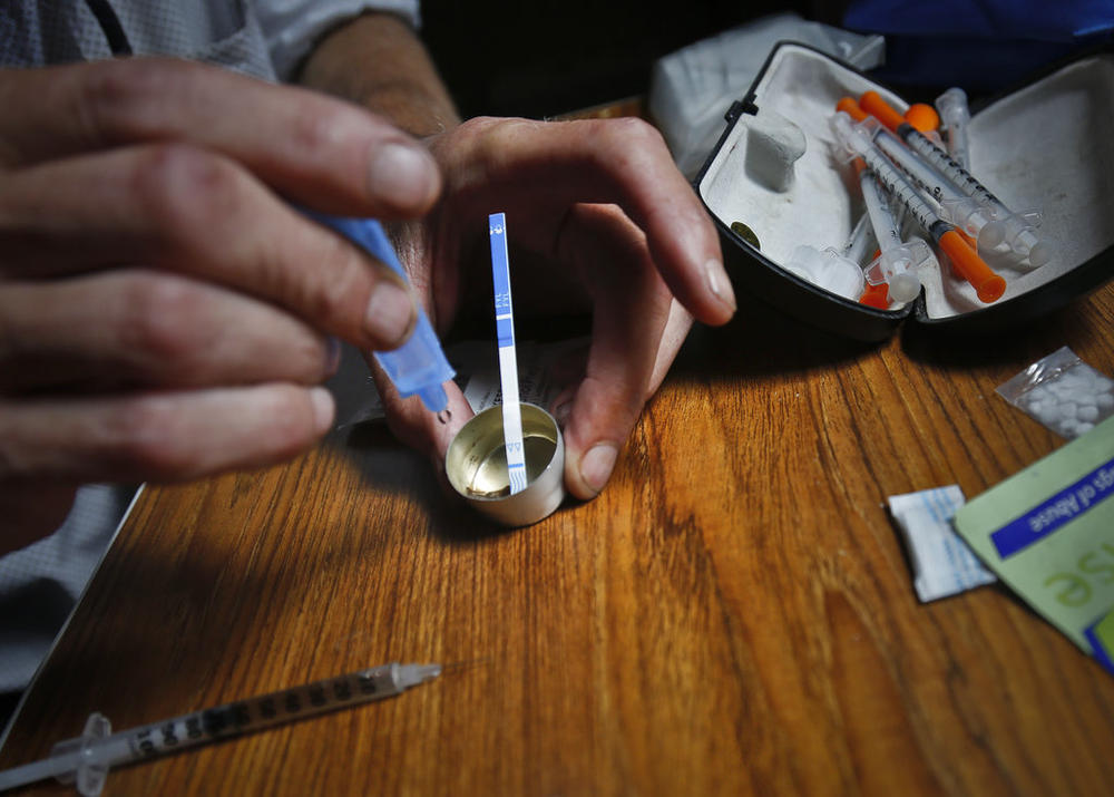A person prepares heroin, placing a fentanyl test strip into the mixing container to check for contamination.