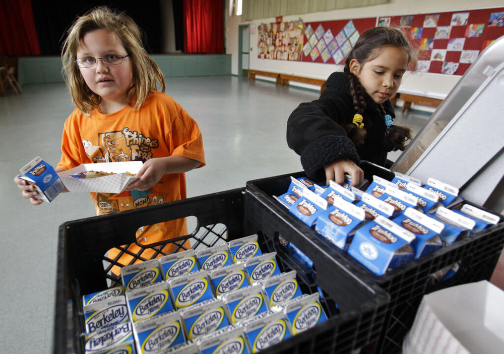 Fairmeadow Elementary School third grade students Ellery Carlson, left, and Tatiana Aboytes, right, pick chocolate milk during a school lunch program 