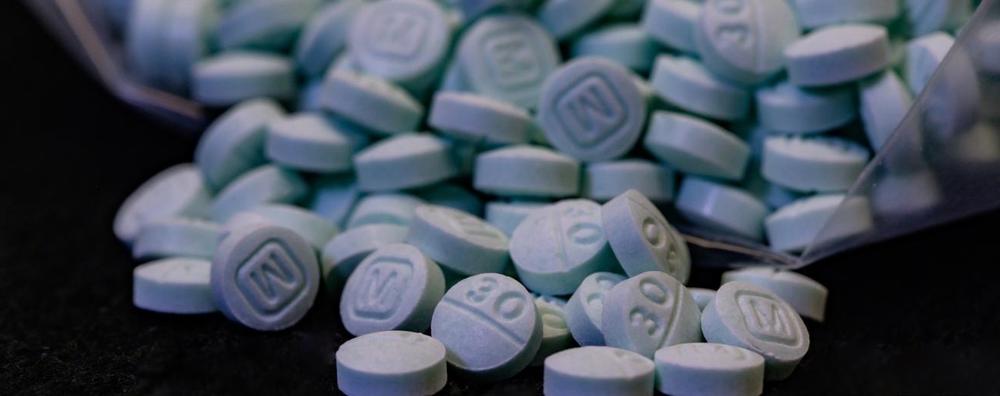File photo of several dozen pills containing fentanyl. They are circular and blue, with one side showing a capital letter M and the other side showing the number 30.