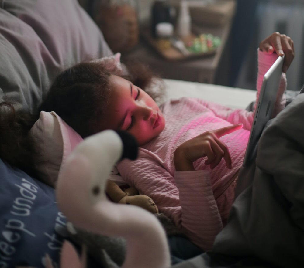 A young girl reads in bed