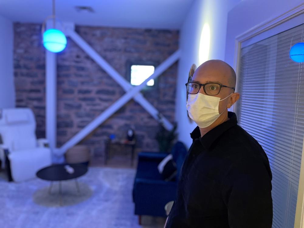 Dr. Michael Muench stands in a room lit with blue light in the Atlanta Field Trip clinic.