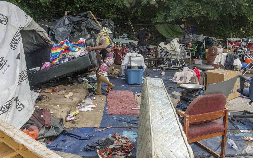 A resident of the Macon homeless encampment between downtown and Interstate 16 struggles to move a couch from their tent before a bulldozer rolls to take it away on June 8, 2022. Macon-Bibb County bulldozed one of the city's largest homeless encampments, saying it was necessary as a public health measure.