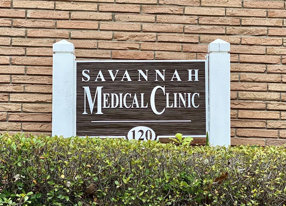 Brick exterior of the Savannah Medical Clinic. A sign for the clinic is displayed in front of the building, behind bushes.