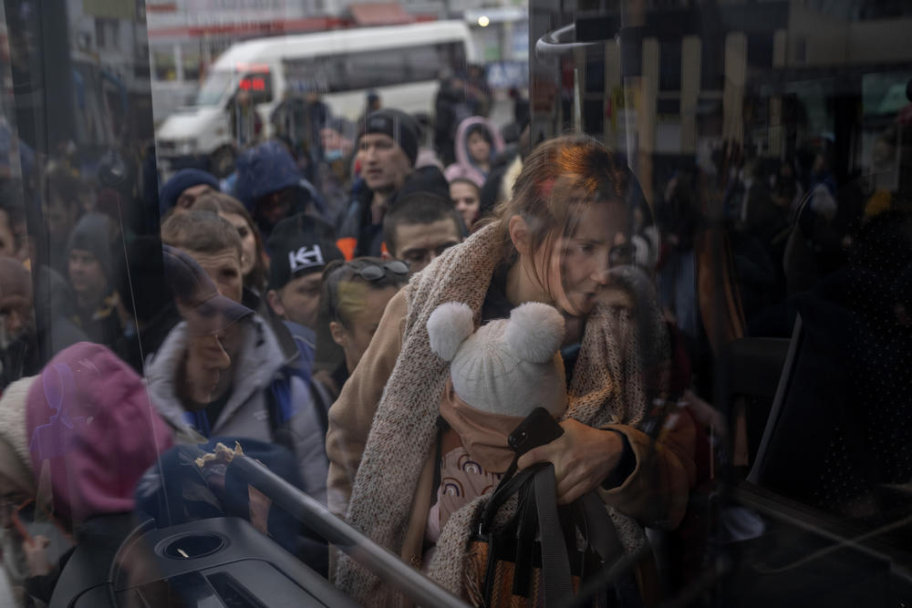 A woman holds her baby as she gets on a bus leaving Kyiv, Ukraine, Thursday, Feb. 24, 2022.