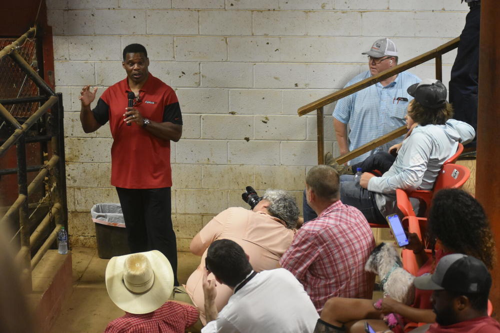 Herschel Walker stumps for votes outside a livestock pen at an auction site in Athens.