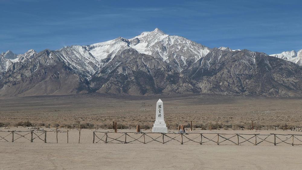 A memorial standing in front of snow-capped mountains.