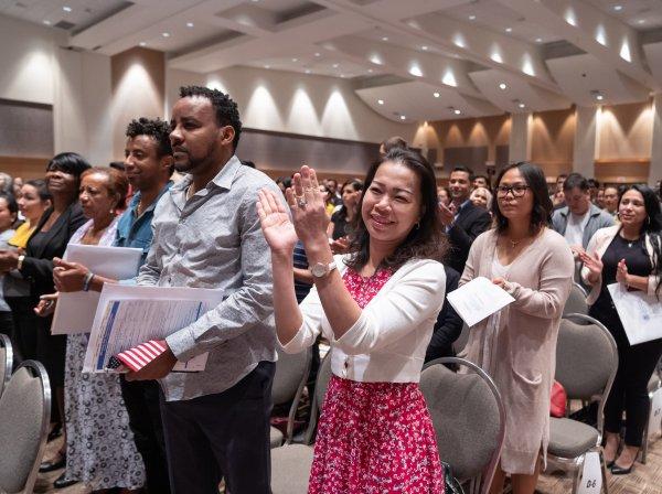 A group of new citizens claps during a naturalization ceremony.