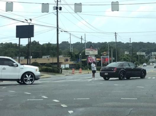 Turning vehicles trap a man in the crosswalk at Spring Street and Riverside Drive as he tries to walk across the busy street.