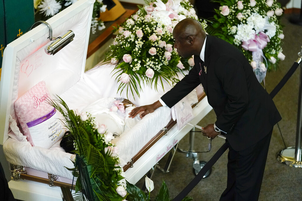 Attorney Ben Crump leans over the casket of Brianna Grier at her funeral.
