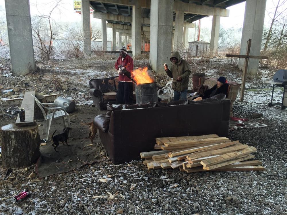 A group of people warm up around a fire at a Gainesville encampment during winter months in 2015. 