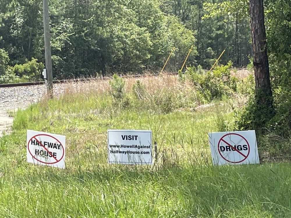 A group of handmade signs opposing a plan for a sober living community on Howell Road.