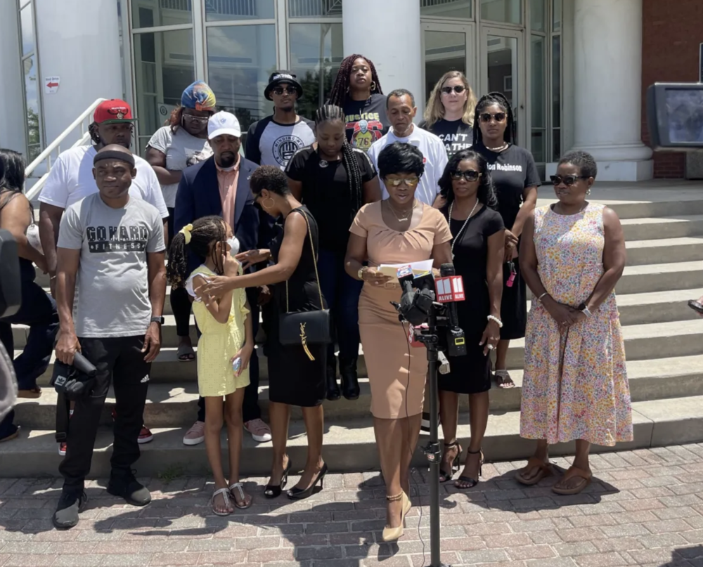 Monteria Robinson, standing before microphones assembled by local media outside of the Clayton County Police Department, is accompanied Aug. 4, 2022, by supporters of her son, Jamarion Robinson, who was killed by police in 2016.