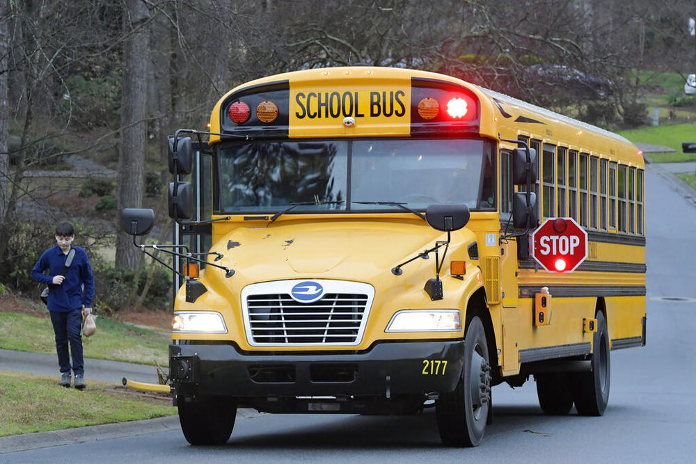 Cobb County School bus moves on street Friday, March 13, 2020, in Kennesaw, Ga. Georgia's second-largest school district. (AP Photo/Mike Stewart, File)