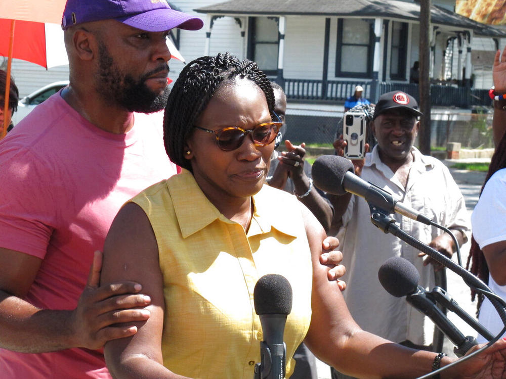 Wanda Cooper Jones, the mother of Ahmaud Arbery, is held by her attorney, Lee Merritt, while addressing supporters gathered for the unveiling of new street signs honoring Arbery on Tuesday, Aug. 9, 2022, in Brunswick, Ga. City officials approved the honor for Arbery, a 25-year-old Black man who was fatally shot in February 2020 after being chased by three white men in pickup trucks who spotted him running in their neighborhood. All three men were later convicted of murder and federal hate crimes.