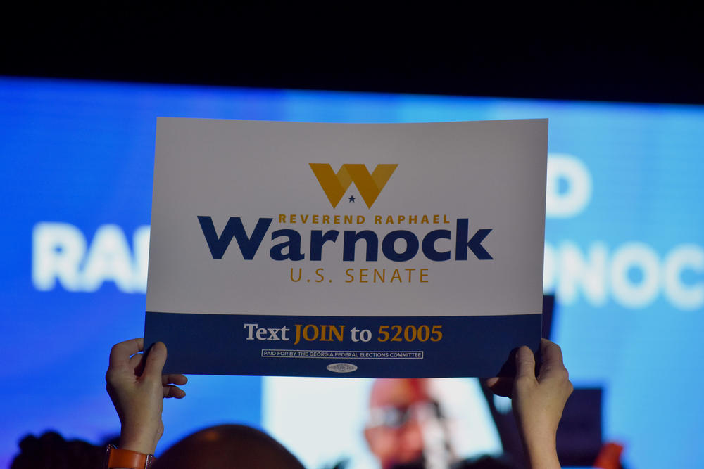 An attendee at the Democratic Party of Georgia state convention holds a sign in support of Sen. Raphael Warnock.