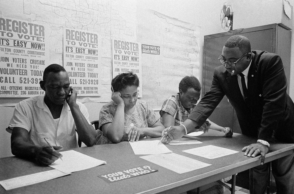 The Rev. Fred C. Bennette Jr., a civil rights movement organizer, right, instructs Black people in Atlanta how to fill out registration forms in 1963.