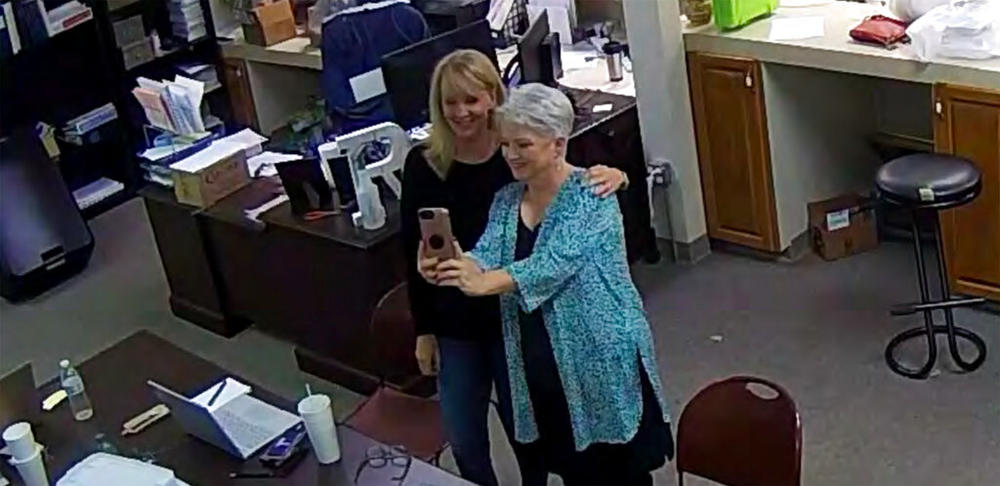 In this Jan. 7, 2021, image taken from Coffee County, Ga., security video, Cathy Latham (right) appears to take a selfie with a member of a computer forensics team inside the local elections office. Latham was the county Republican Party chair at the time. The computer forensics team was at the county elections office in Douglas, Ga., to make copies of voting equipment in an effort that documents show was arranged by Sidney Powell and others allied with then-President Donald Trump.