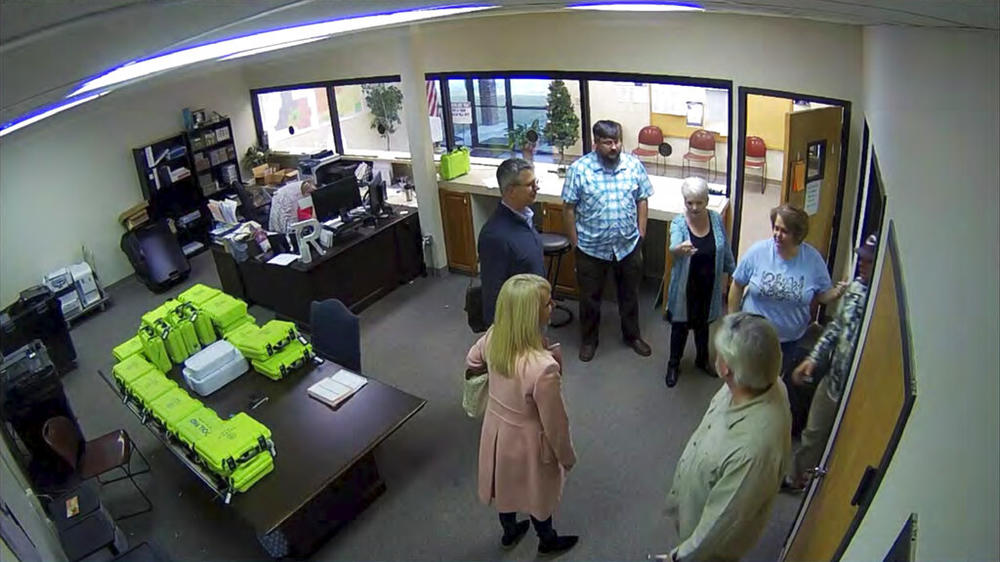 This Jan. 7, 2021, image taken from Coffee County, Ga., security video, appears to show Cathy Latham (center, long turquoise top), introducing members of a computer forensic team to local election officials. Latham was the county Republican Party chair at the time. The computer forensics team was at the county elections office in Douglas, Ga., to make copies of voting equipment in an effort that documents show was arranged by Sidney Powell and others allied with then-President Donald Trump.