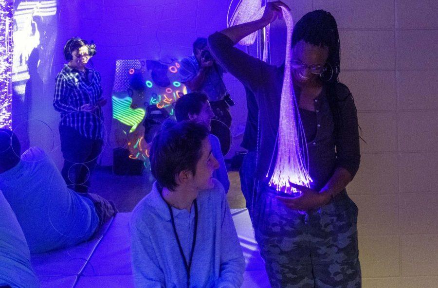 Central High School senior Gabe Deegan watches assistant teacher and parapro Madelynn Washington hold a stream of optical fiber lights in the school’s new sensory room on Oct. 25, 2022.