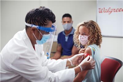 A pharmacist gives a girl a bandaid after a vaccine shot