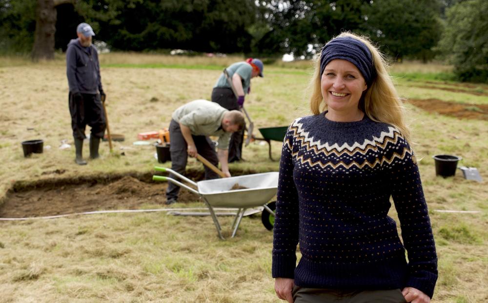 A woman smiles at a dig site.