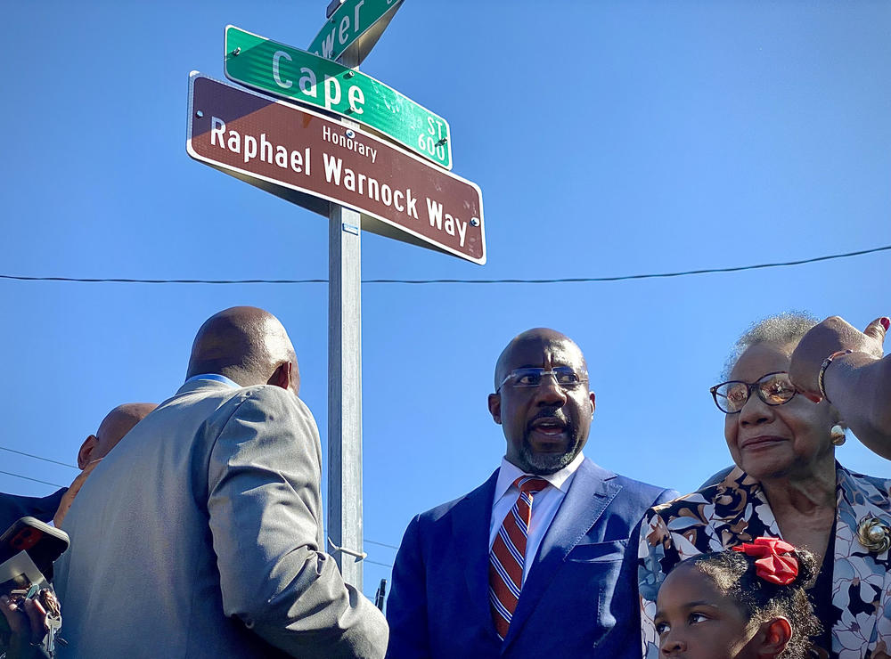 Sen. Raphael Warnock stands in front of the newly unveiled street sign for ‘Raphael Warnock Way’ in Savannah.