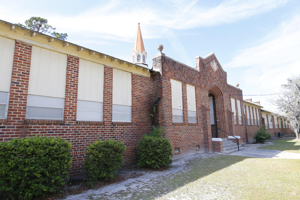 A boarded up brick building is shown.