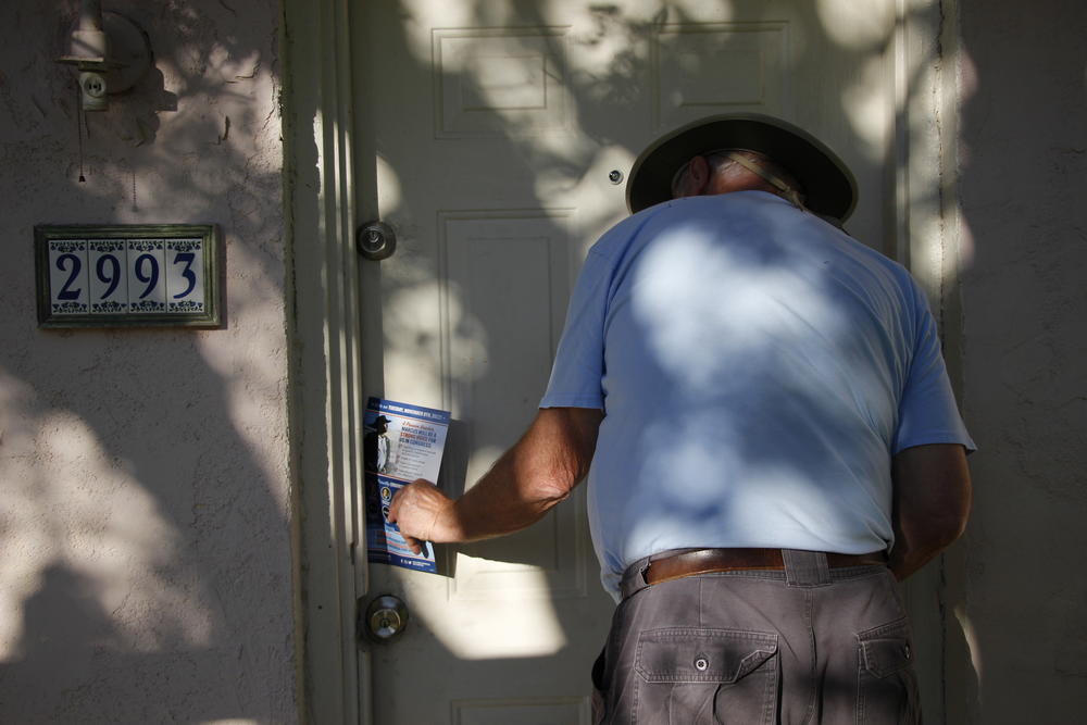 Volunteer canvasser Kent Buis places a Marcus Flowers flyer in the door of a home in Powder Springs, Ga. 