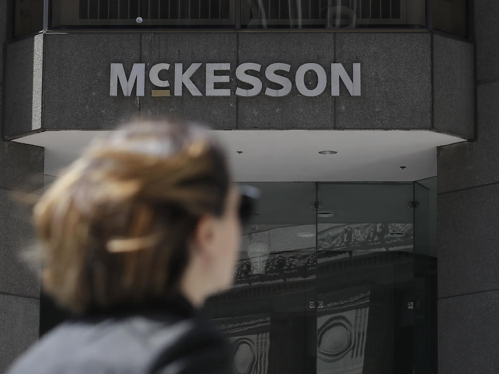 A woman with sunglasses walks in front of a McKesson building