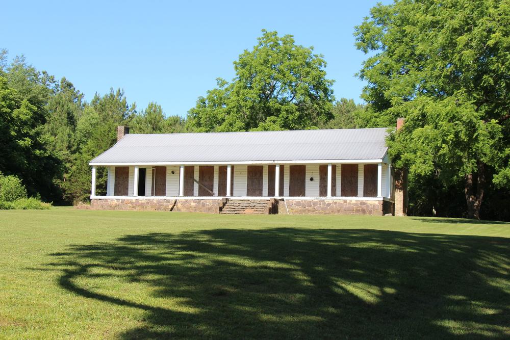A white-painted, one-story house with a porch in shown.