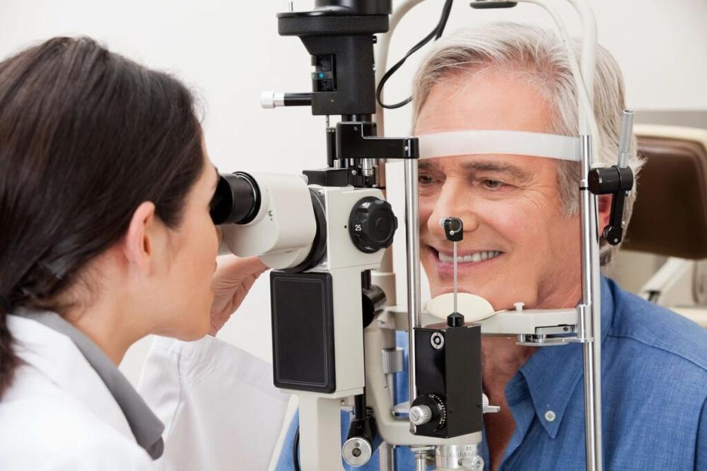 Smiling man gets his eyes checked by optometrist