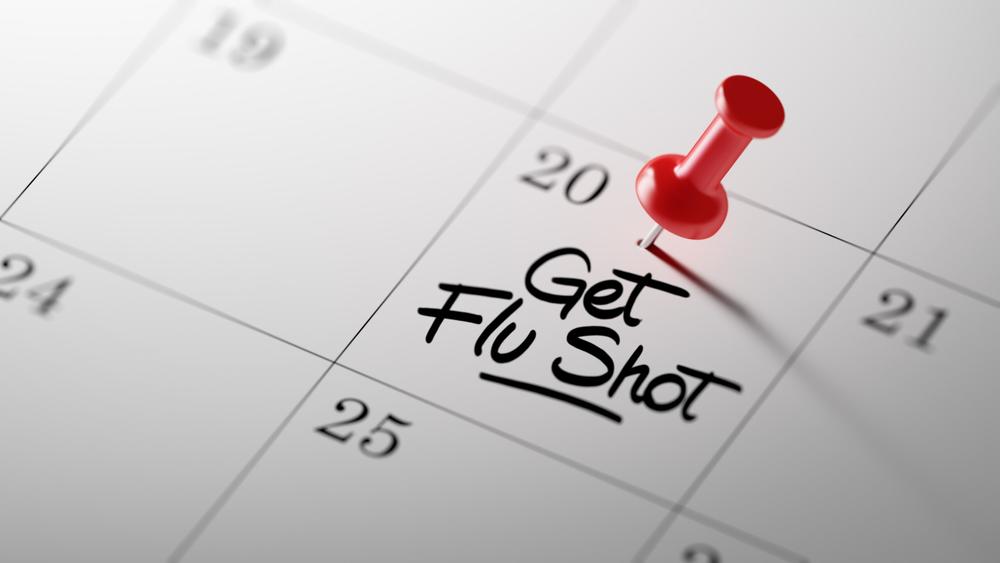 A calendar with a red thumbtack marking the date to get a flu shot