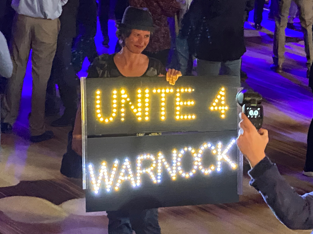 A supporter displays a sign at Raphael Warnock's campaign event on Dec. 6, 2022