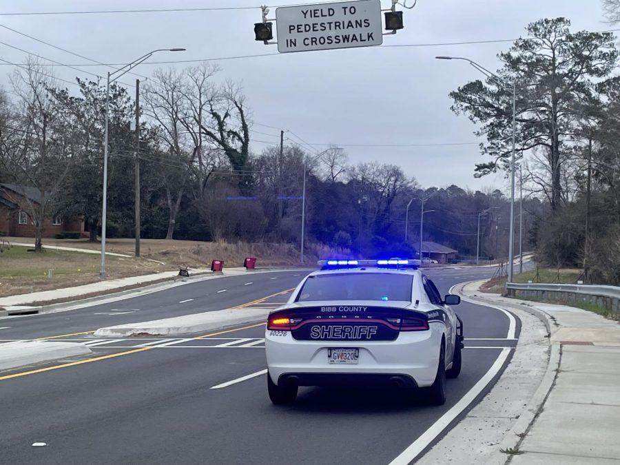 Laura Corley | The Macon Newsroom  A Bibb County sheriff deputy’s car with blue lights activated near a pedestrian crosswalk on Jeffersonville Road in Macon.