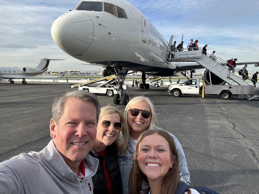 Governor Brian Kemp with family, a plane in the background.