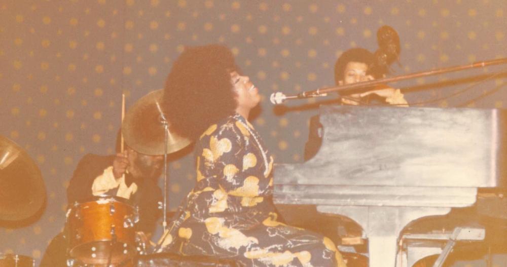 Roberta Flack singing and playing a piano.