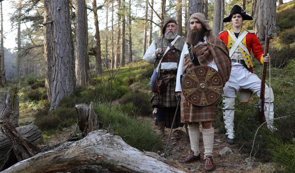 Drama reconstruction of Jacobites Rob Roy and his father Donald McGregor, and an English government trooper standing in the forest.