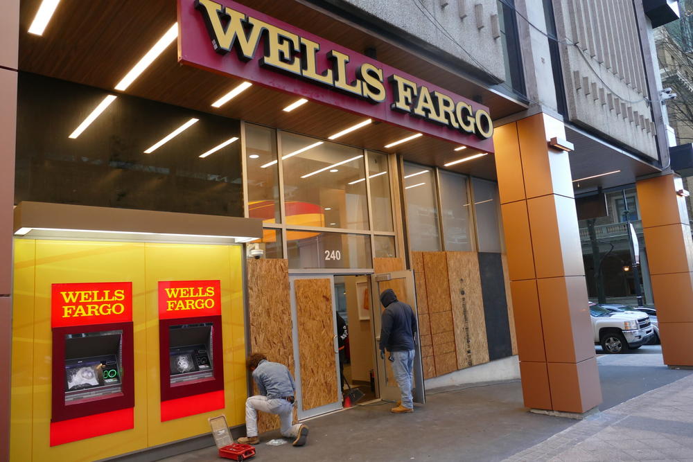 Workers boarded up shattered windows and doors at the Wells Fargo branch on Peachtree Street in downtown Atlanta Monday afternoon. The bank was apparently targeted by rioters for its support of the Atlanta Police Foundation, which backs a planned training center for law enforcement. 