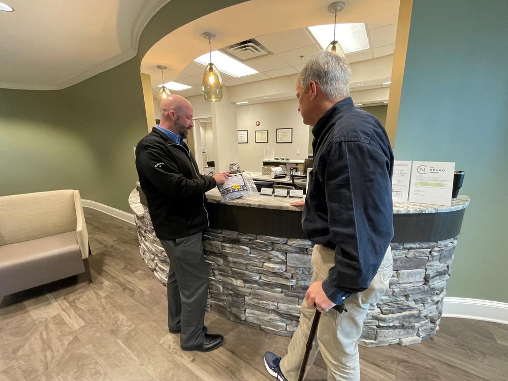 Dr. Daniel Cobb and Chris Griffin, his patient, speak at the counter in the lobby of the Neuro Center in Gainesville, Georgia.